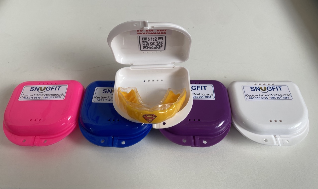 Snugfit custom mouthguards in pink, blue, purple, and white protective cases